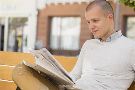 Young Man Sitting On The Bench And Reading Newspapers Stock Photo