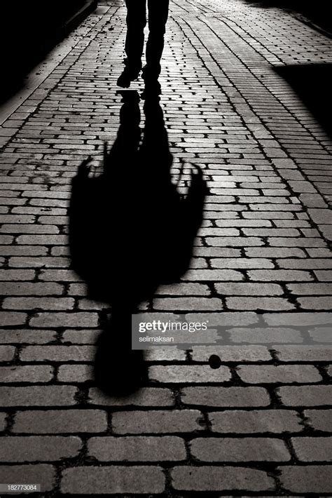 Black And White Shadow Of Man Walking On Sidewalk Stock