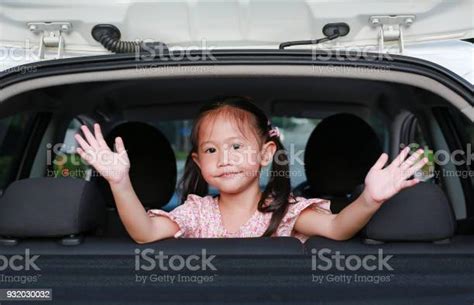 Cute Asian Girl In A Backseat Of A Car Waving Goodbye Stock Photo