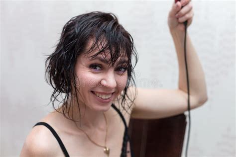 A Brunette Woman With Wet Hair After Shower Stands At The Mirror With