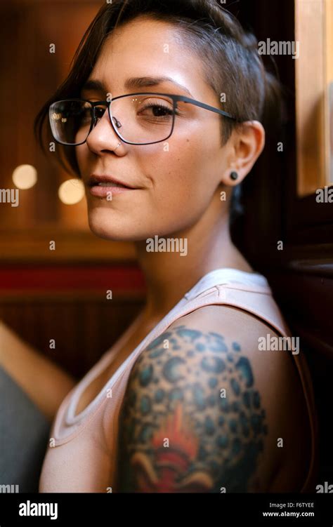 Portrait Of Tattooed Young Woman With Nose Piercing Wearing Glasses