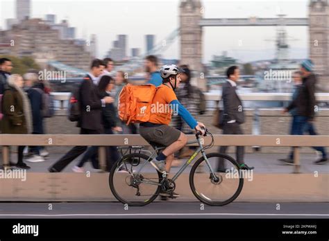 A Just Eat cycle courier riding an e-bike across, London Bridge, London