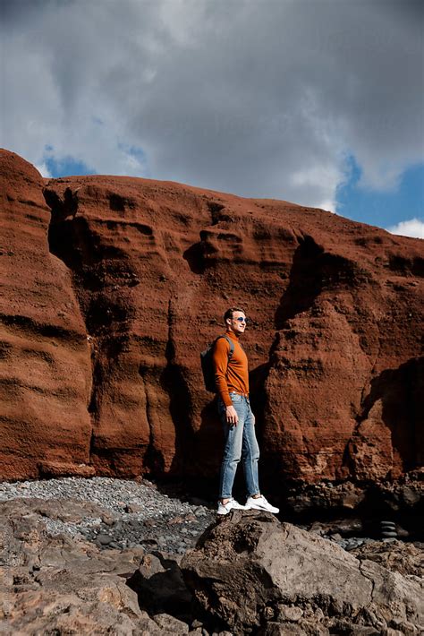 Stylish Man With Backpack Standing Near Big Orange Stones By Alina