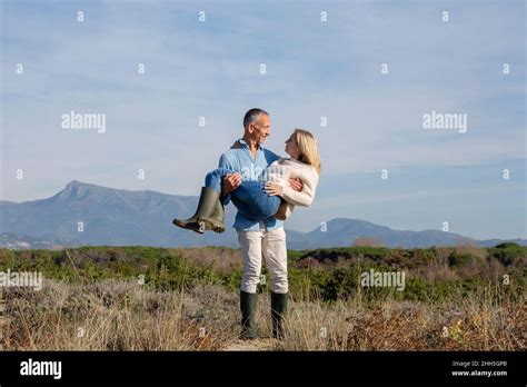 Romantic Man Carrying Woman Standing Amidst Plants Stock Photo Alamy