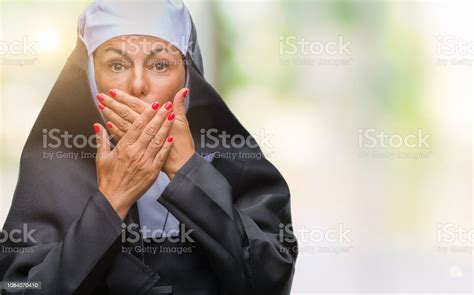 middle age senior christian catholic nun woman over isolated background shocked covering mouth