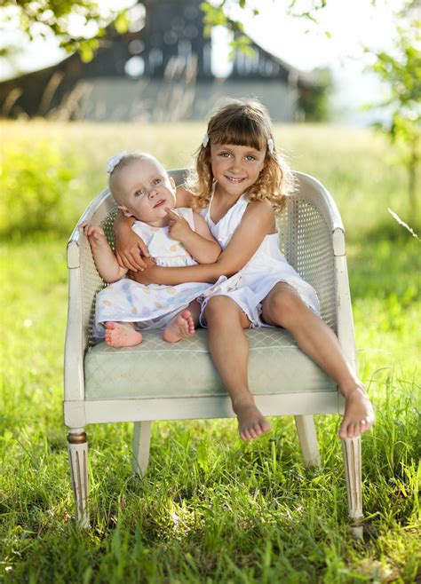 Two Cute Little Sisters Laughing And Playing In Green Sunny Park