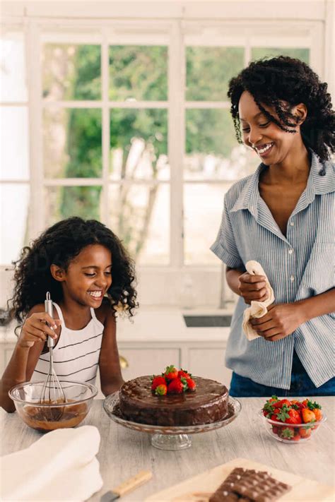 Beautiful Girl Enjoying Making Cake With Her Mom At Home Mother And Daughter Having Great Time