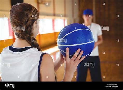 Female Basketball Player Practicing With Male Coach In Court Stock