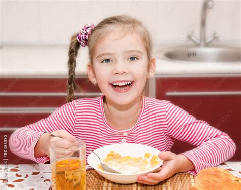 Cute Smiling Little Girl Having Breakfast Cereals With Milk Stock Photo