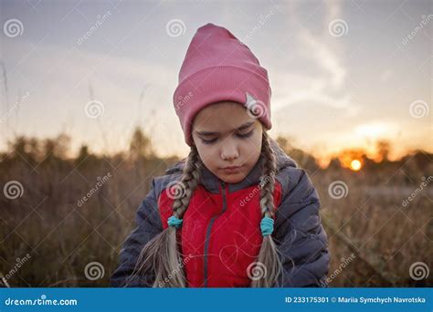 Portrait Of Pensive Preteen Girl Standing Among A Dry Meadow Over