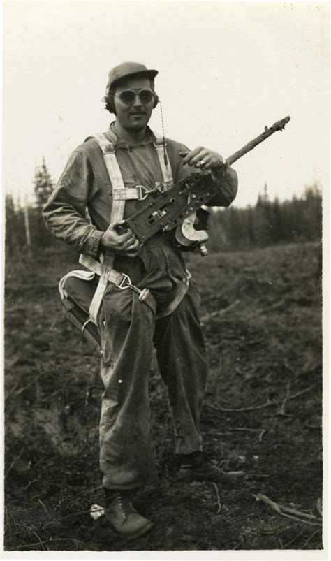 American Soldier With Parachute And Machine Gun Standing In Dirt Field