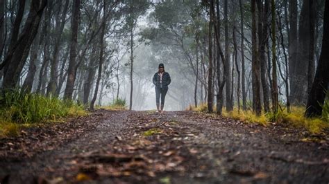 Image Of Wide Shot Of Woman Walking Towards Camera On Foggy Mountain