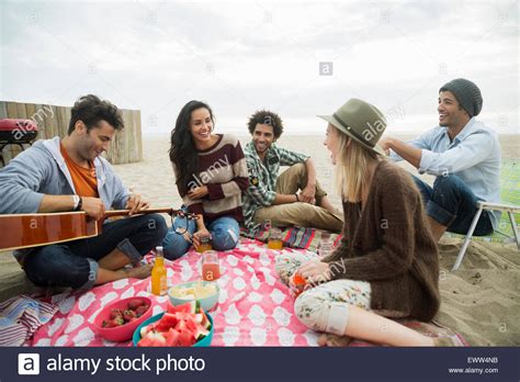 Use them in commercial designs under lifetime, perpetual & worldwide rights. Friends hanging out playing guitar picnicking on beach ...