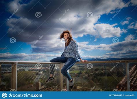 Beautiful Young Girl Sitting On A Railing With A Spectacular View Stock