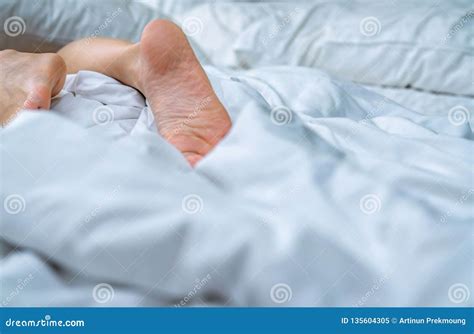close up woman bare feet on the bed over white blanket and bed sheet in the bedroom of home or
