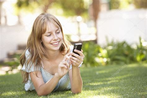 Teenage Girl Laying In Park Using Mobile Phone — Stock Photo