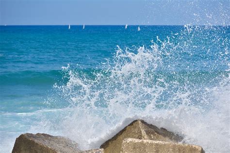 Splash Water Of Sea Wave Attack To The Rock Phot With Outdoor Sunny