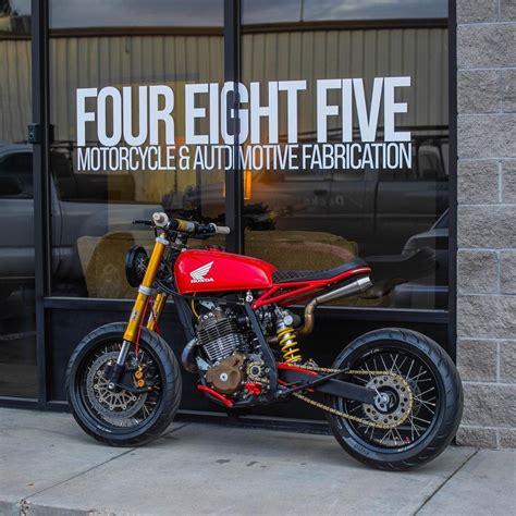 A Red And Black Motorcycle Parked In Front Of A Store Window With The