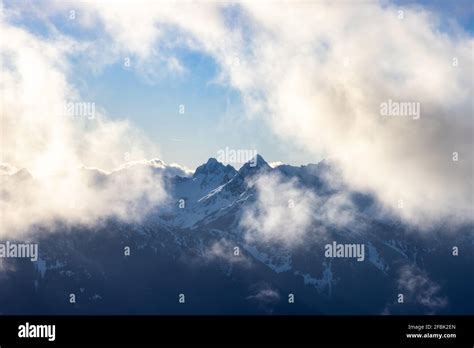 Rugged Mountain Peaks Covered In Snow And Clouds Stock Photo Alamy