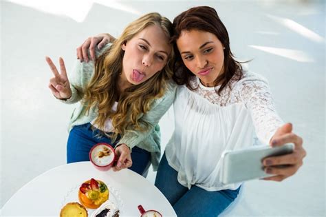 Premium Photo Two Girls Take A Selfie While Eating And Drinking Coffee