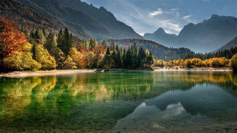 Calm Body Of Water Surrounded With Trees And Mountains
