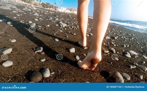 Closeup Rear View Image Of Female Feet Walking Away On The Sea Beach