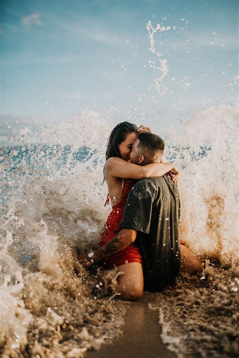Engaged Couple Kissing As A Wave Crashes Down On Them In Maui Hi