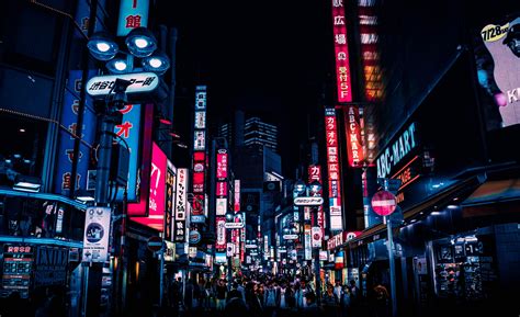 A City Street Filled With Lots Of Neon Signs And Tall Buildings In The Night Time