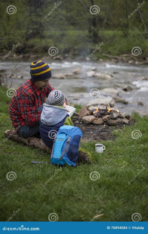 Il Padre Ed Il Figlio Che Si Siedono Vicino Ad Un Fuoco Di Accampamento Al Campeggio E Sono L