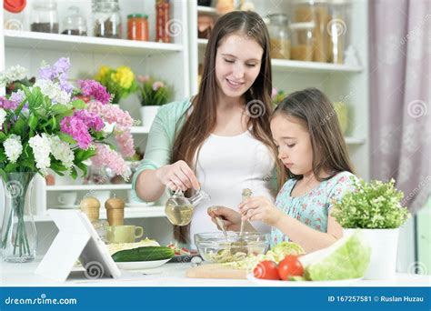Портрет улыбаясь беременных мать и дочь готовит на кухне Стоковое Изображение изображение