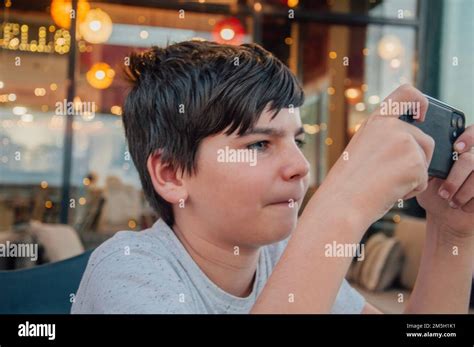 Portrait Of Young Boy Playing Mobile Phone Games In A Bar With