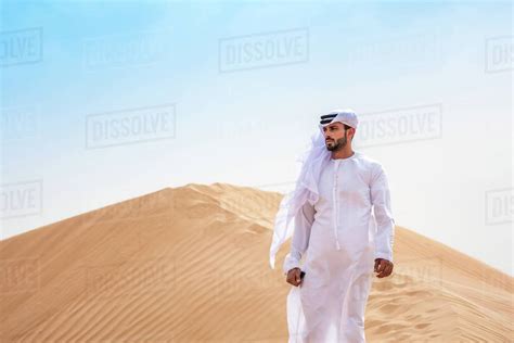 Middle Eastern Man Wearing Traditional Clothes On Desert Dune Dubai