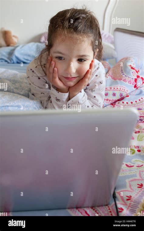 Little Girl Lying In Bed And Playing With A Laptop In His Bedroom She