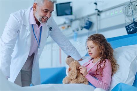 Friendly Doctor Taking Care And Playing With Little Girl Stock Photo