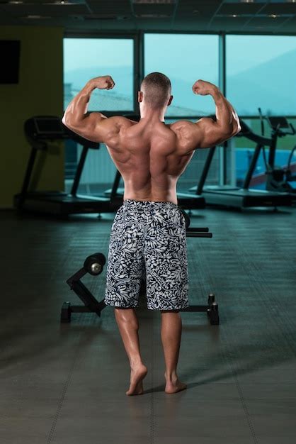 Premium Photo Muscular Man Flexing Muscles In Gym