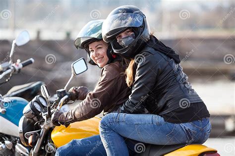 girl a passenger sitting behind female motorcyclist on a bike cheerful females riding on the