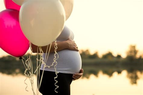 Premium Photo Pregnant Woman Holding Her Belly And Balloons On A Sunset