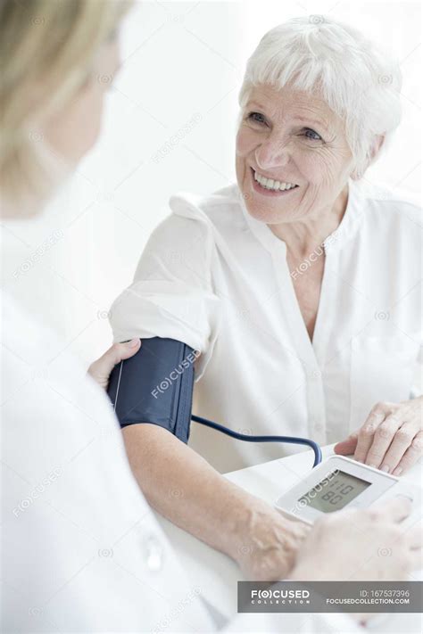 Female Doctor Taking Blood Pressure Of Senior Woman — Examining