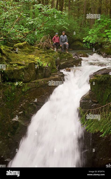 Two Hikers Stand At The Top Of Sawmill Creek Falls In The Tongass
