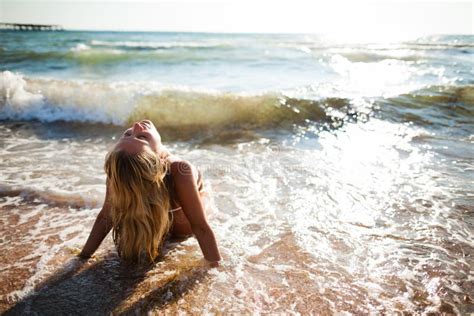 Joven Mujer Rubia En Bikini Blanco Sentada En El Borde Del Agua Del Mar En Las Olas Espuma Y