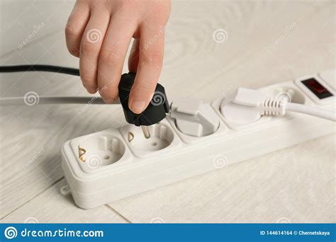 Woman Inserting Power Plug Into Extension Cord On Floor Stock Photo