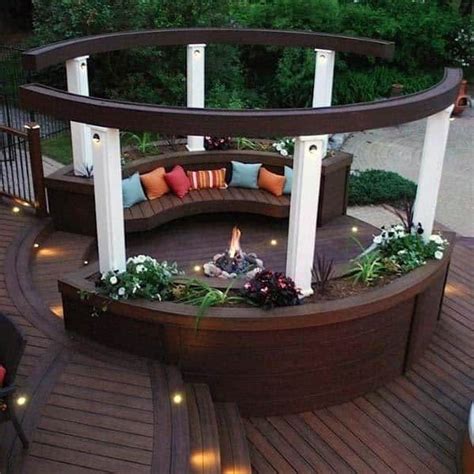 A Fire Pit Surrounded By Wooden Decking With Lights On The Sides And