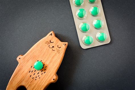 premium photo a wooden toy sleeping cat and a blister of green pills on a black background