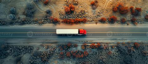 A red semi truck is driving down a road in a desert. The truck is the