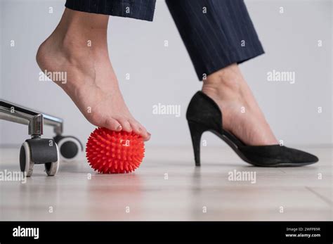 Business Woman Massages Her Feet On A Massage Ball With Spikes Stock
