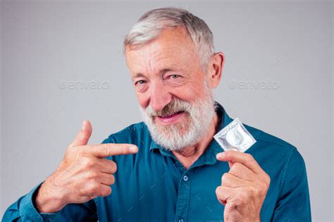 Caucasian Old Senior Man Holding Packed Rubber Latex Condom In Studio