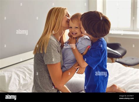 Mère et enfants embrassent et embrassent sur le lit dans la chambre Fête des mères Maman et