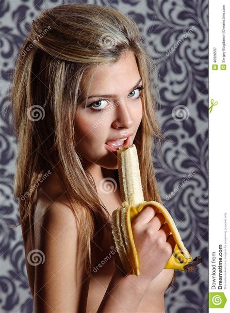 A Beautiful Young Woman Holding A Banana In Her Hand And Looking At The Camera With An Intense