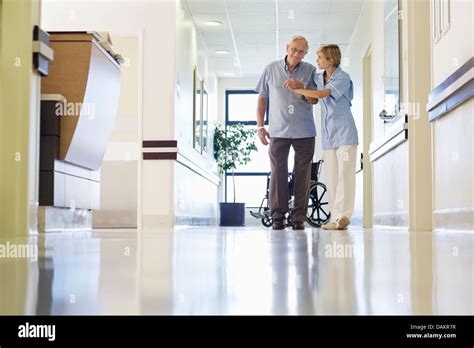 Nurse Helping Patient Walk In Hospital Hallway Stock Photo Alamy