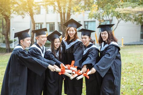 Happy Students In Graduation Gowns Holding Diplomas On University